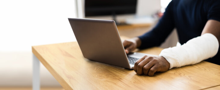 Injured Worker Compensation. Broken Arm African Man On Computer