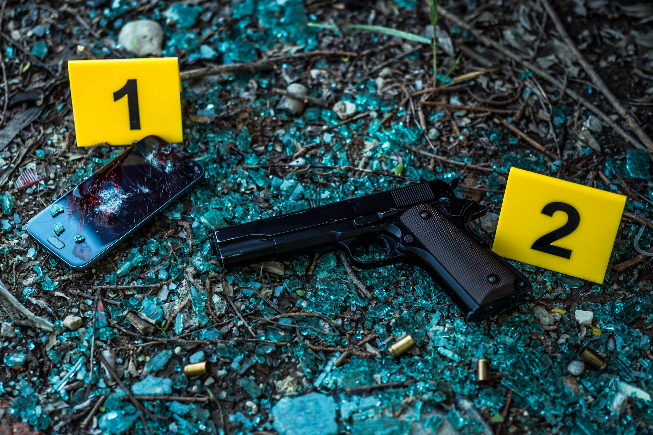 Bullet casings and gun on the ground. Crime scene.