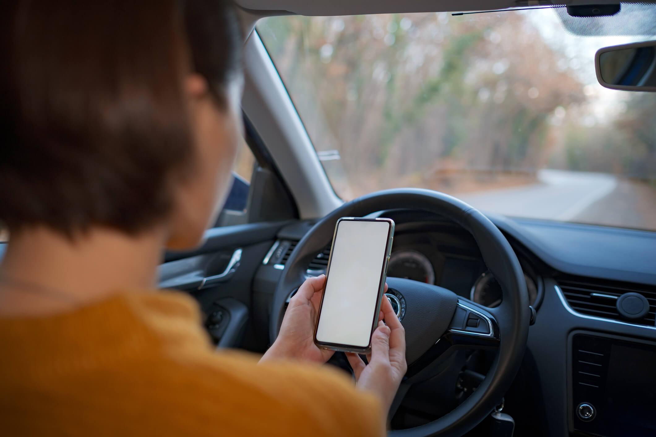 Mockup image of a woman holding and using mobile phone with blank screen while driver a car. People, Driving, Navigation and Transportation Concepts