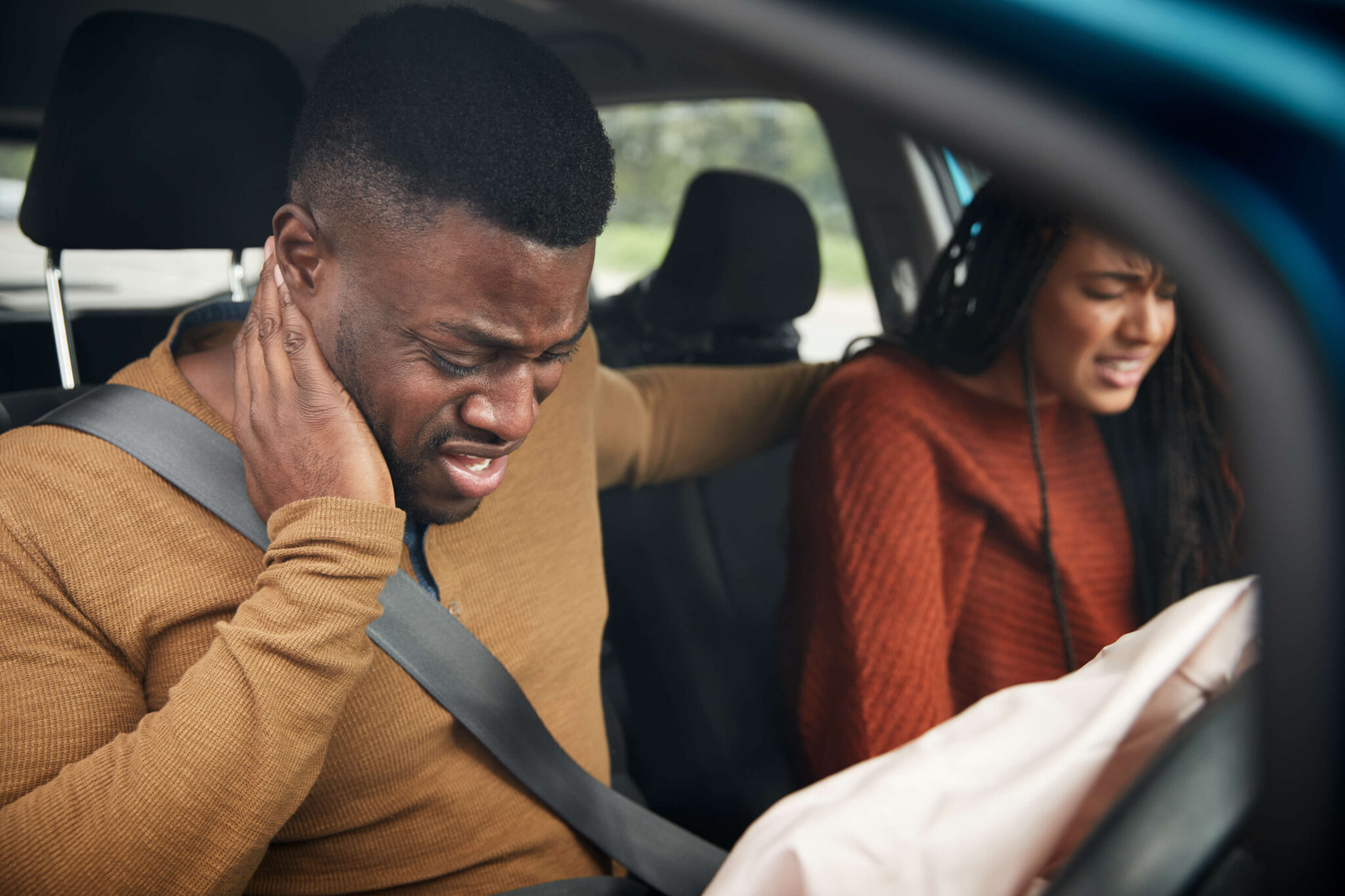 Back and neck injury settlement after a car accident: driver holding his neck after a crash