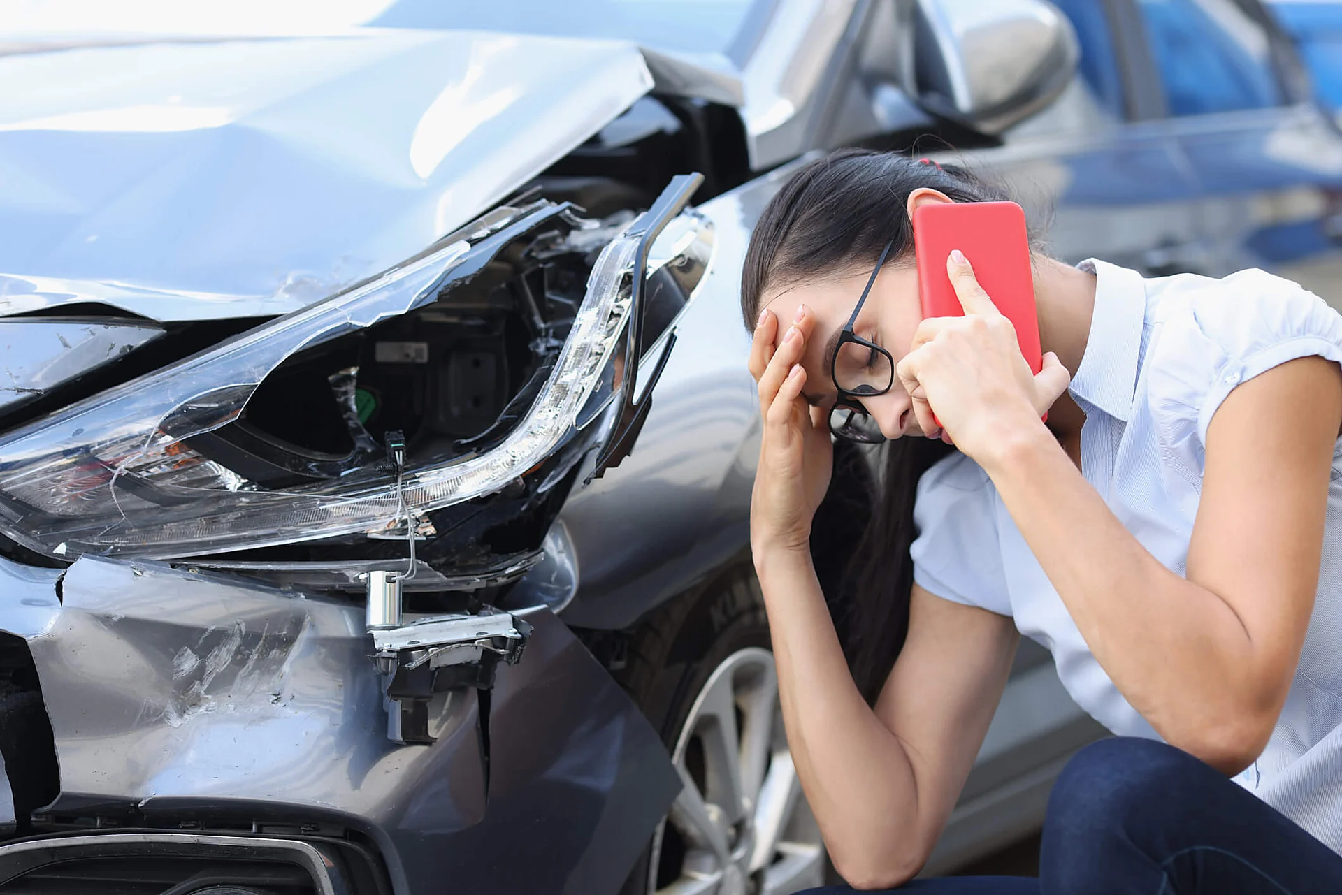 Greenville car accident lawyer for a driver on the phone beside her crushed bumper